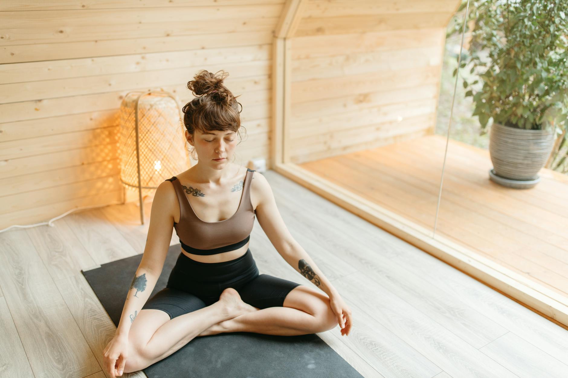 tattooed woman in activewear meditating