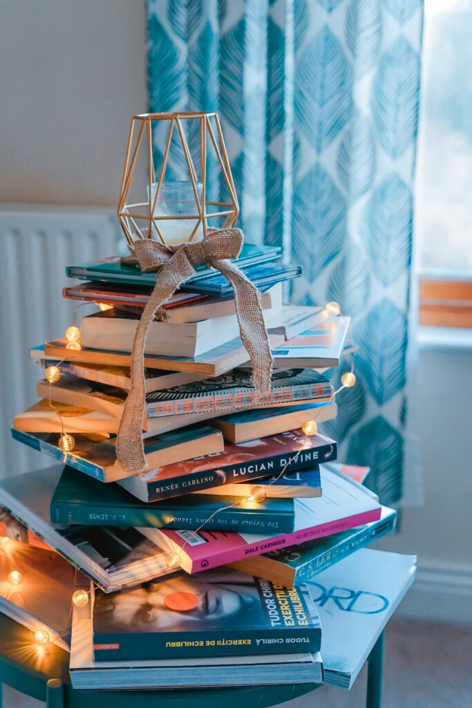 stack of books wrapped in twinkle lights to look like a winter Christmas tree