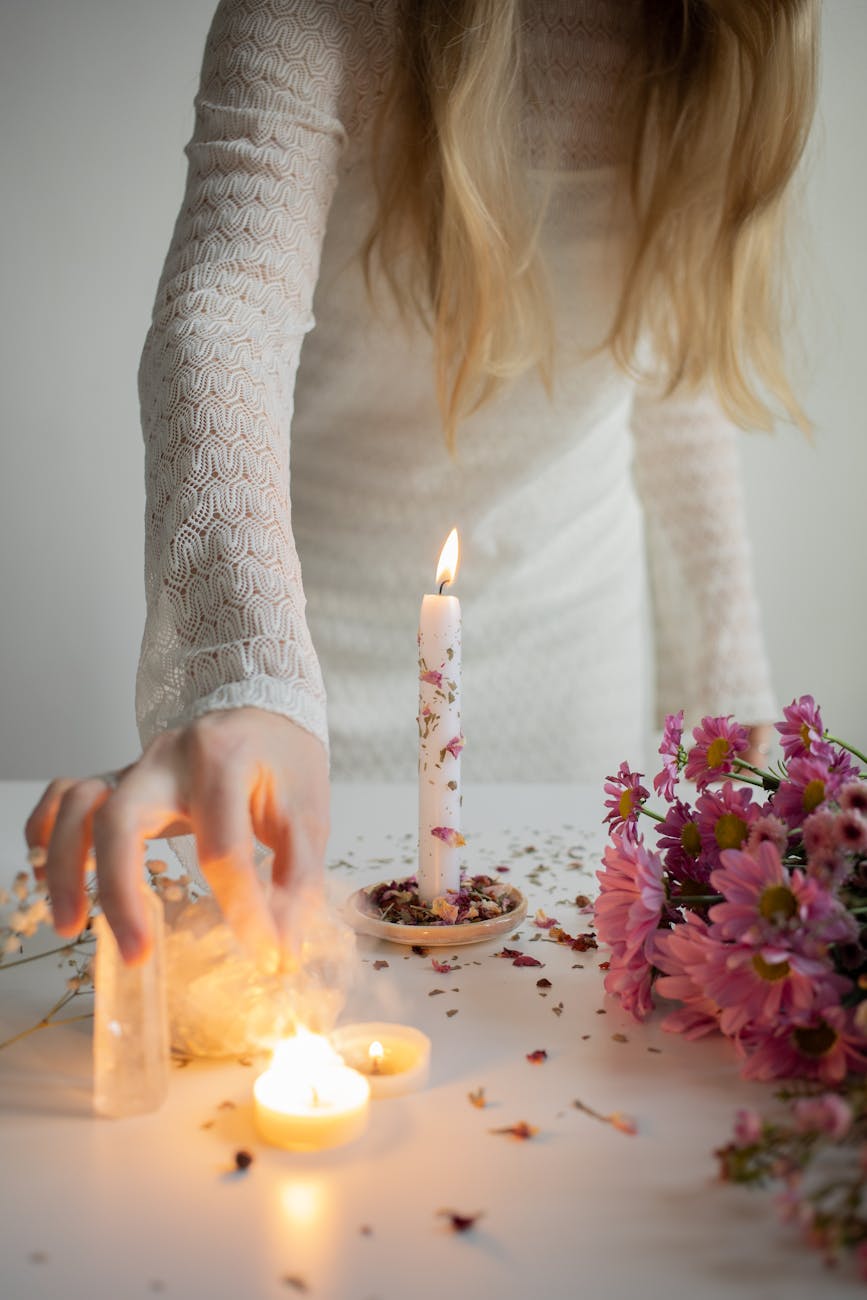 woman standing next to a table with burning candles flowers and crystals