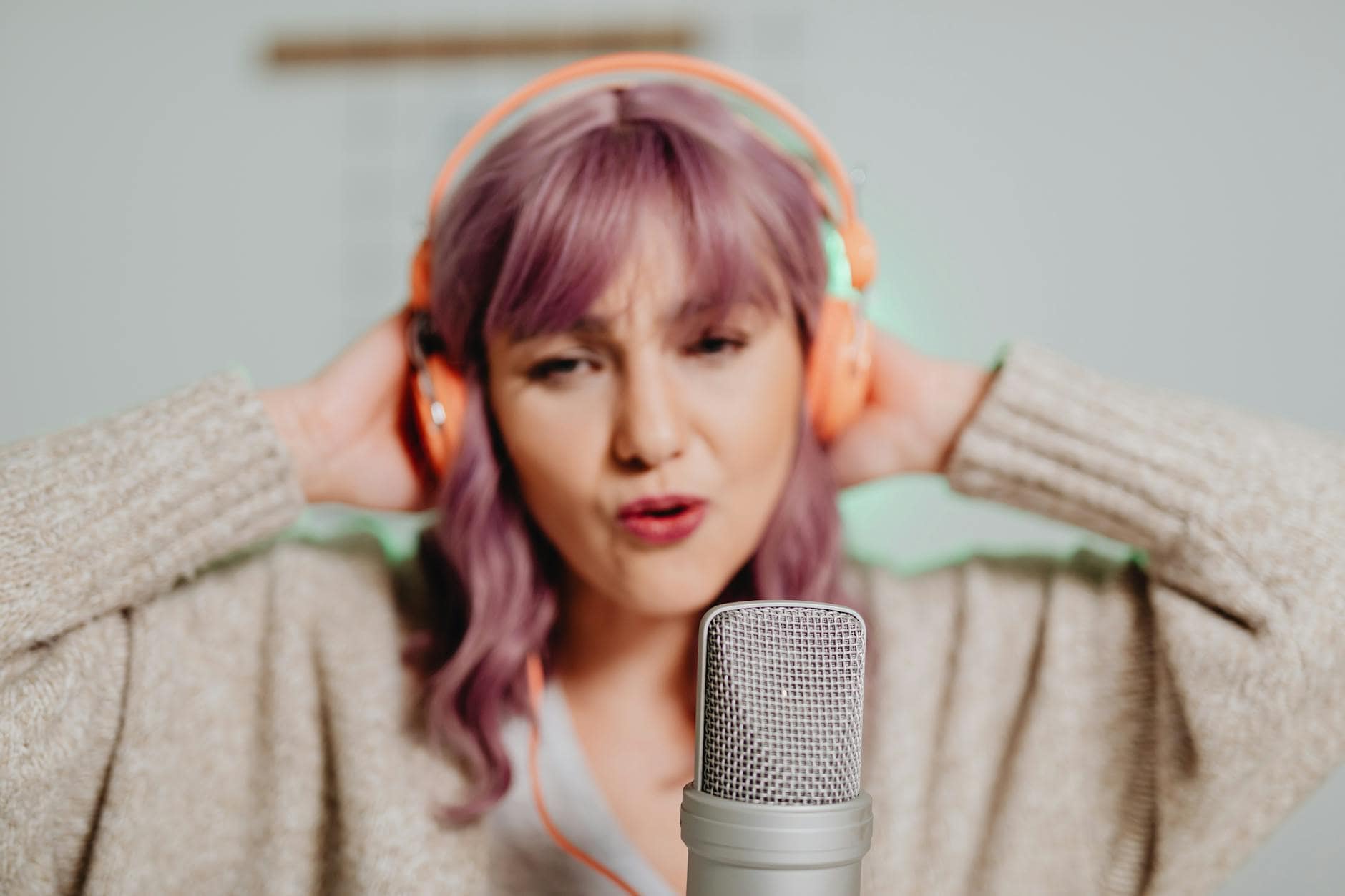 woman in brown sweater wearing orange headphones
