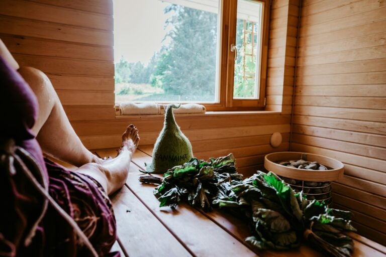 woman enjoying a sauna with a birch whisk and wool hat