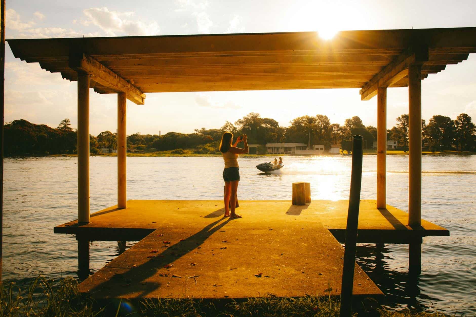 girl taking photos by lakeside at sunset