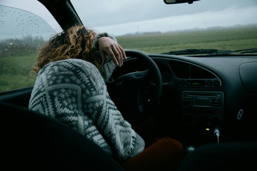 Anxious woman sitting in her car, experiencing a setback