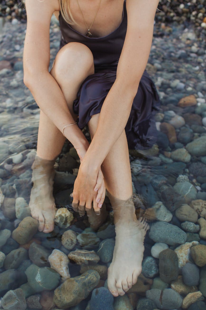 woman in blue sleeveless dress sitting on rocky shore