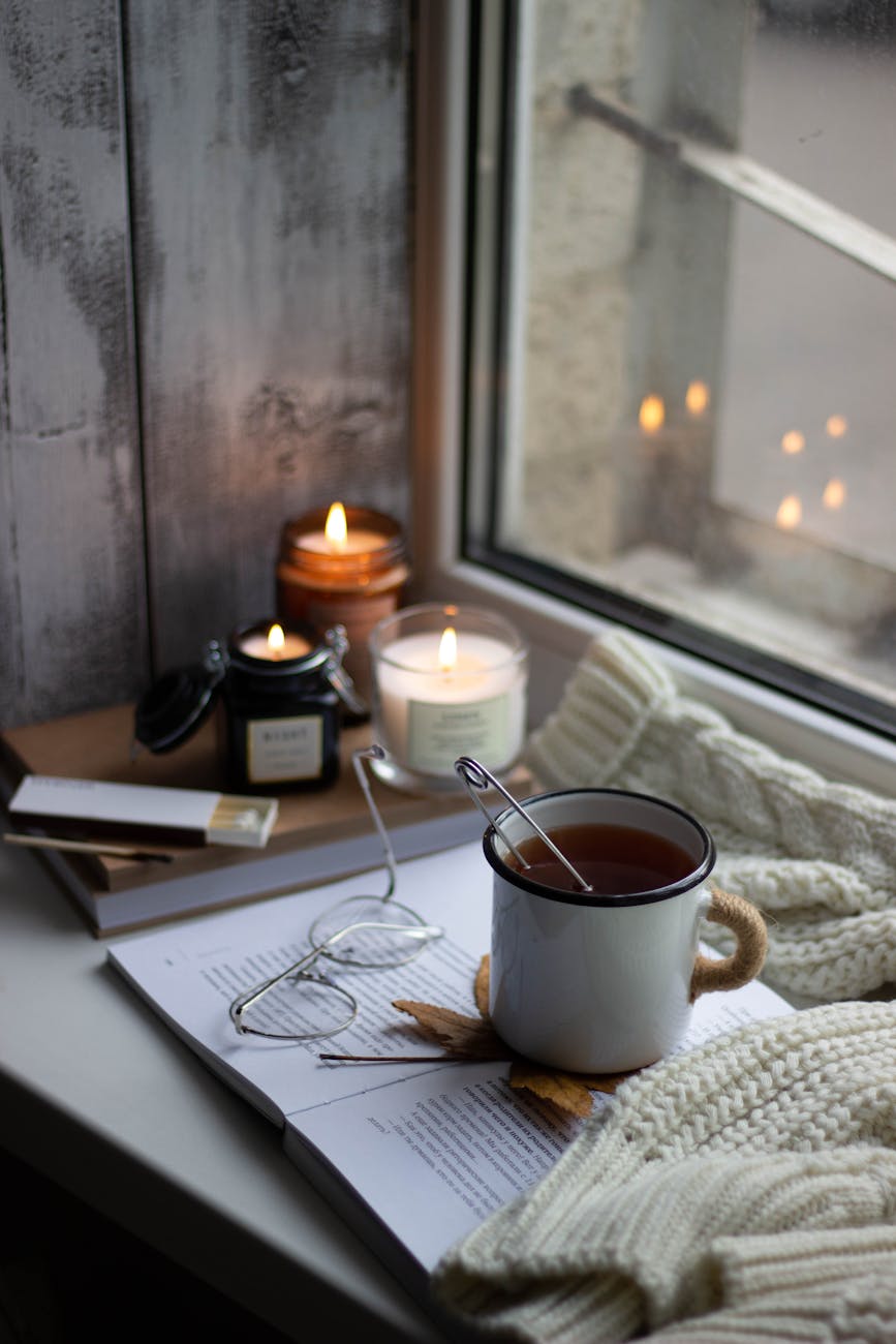 windowsill with autumnal decorations a book eyeglasses and a cup of tea