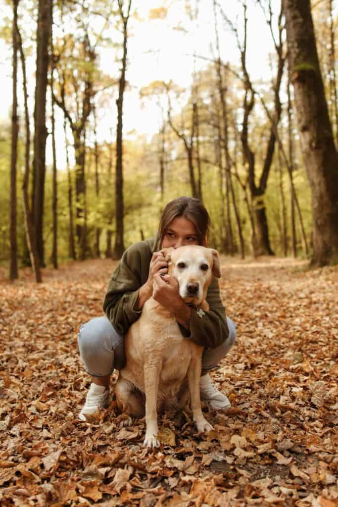 a woman hugging her labrador retriever dog from the back