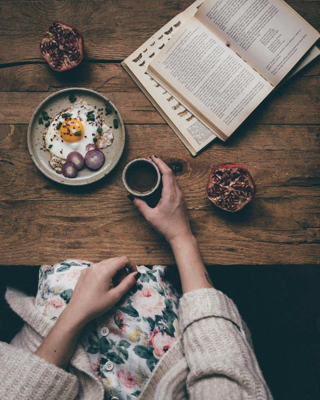 crop woman having breakfast and reading