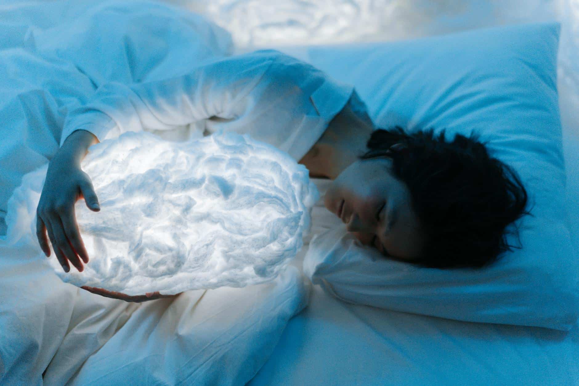 a woman sleeping on the bed while hugging a cloud pillow