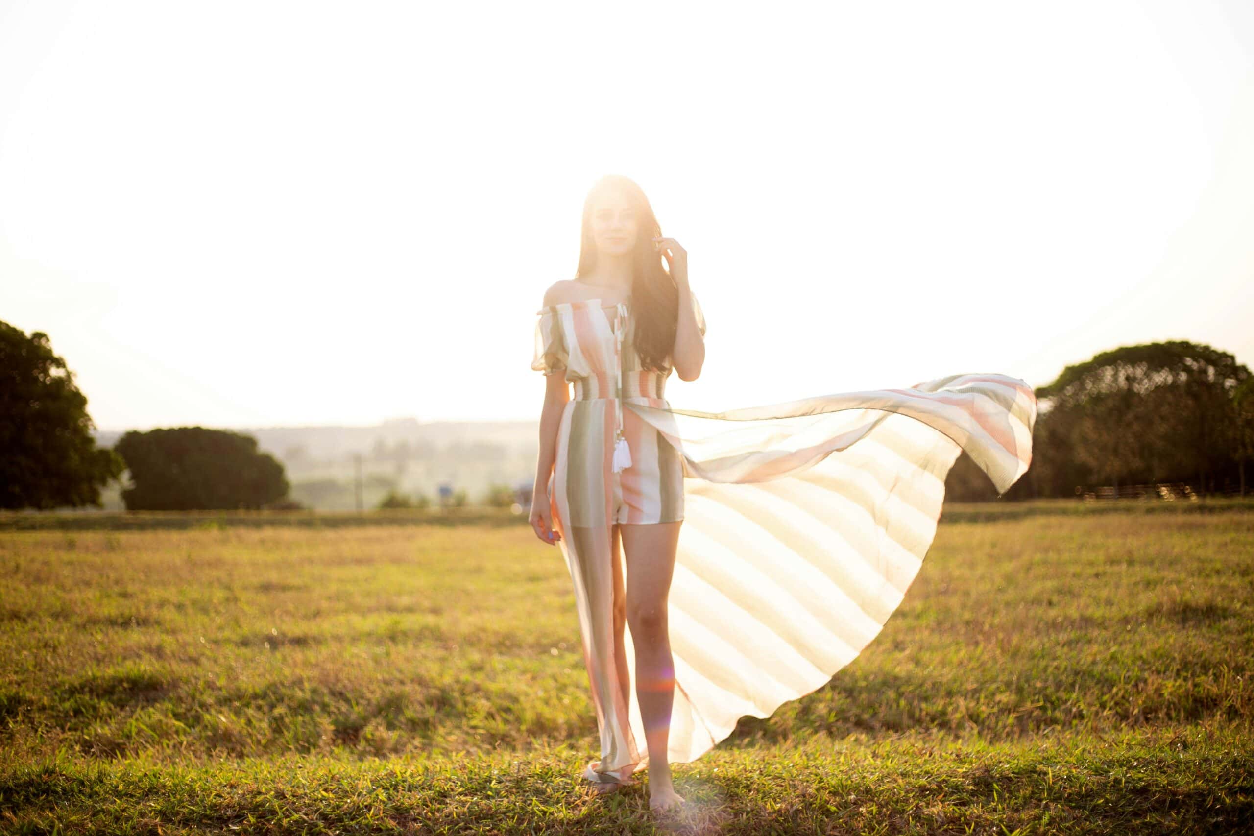 Woman standing outdoors in a flowing dress, symbolizing feminine energy and cycle awareness.