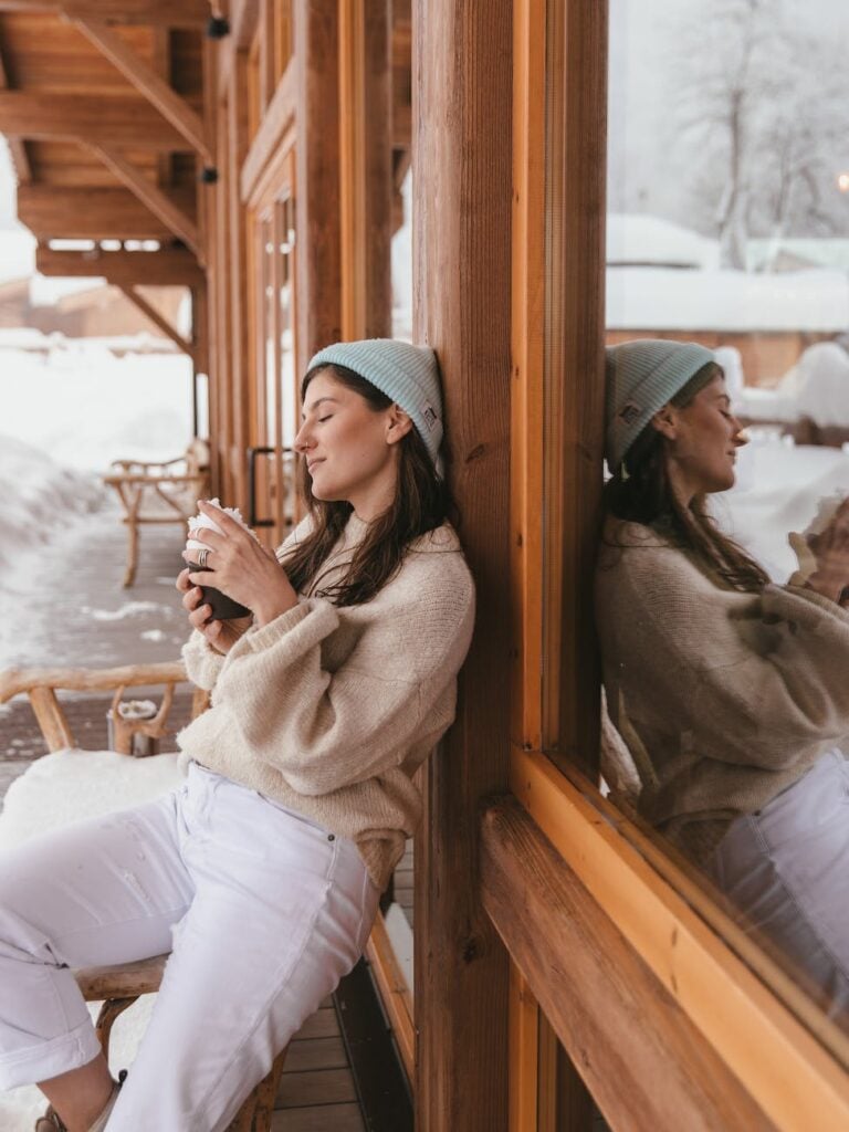 woman in her sweater leaning on wooden wall