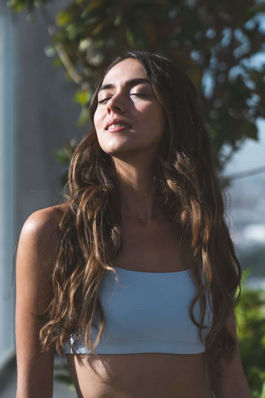 a woman in white crop top smiling with her eyes closed