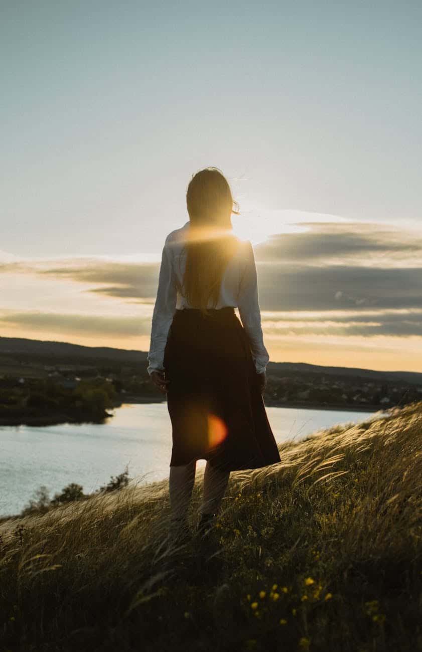woman walking on hill above river