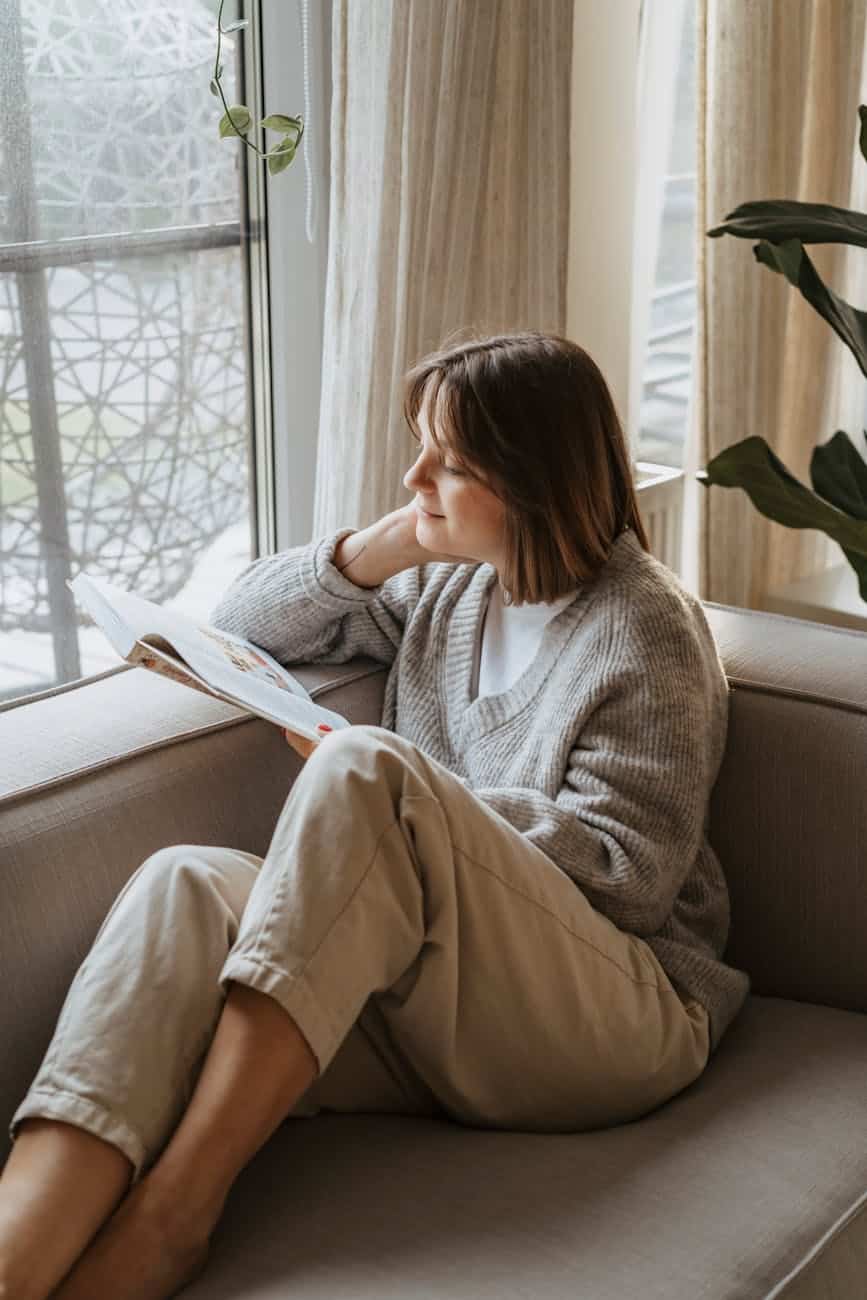 a woman reading a book on a couch