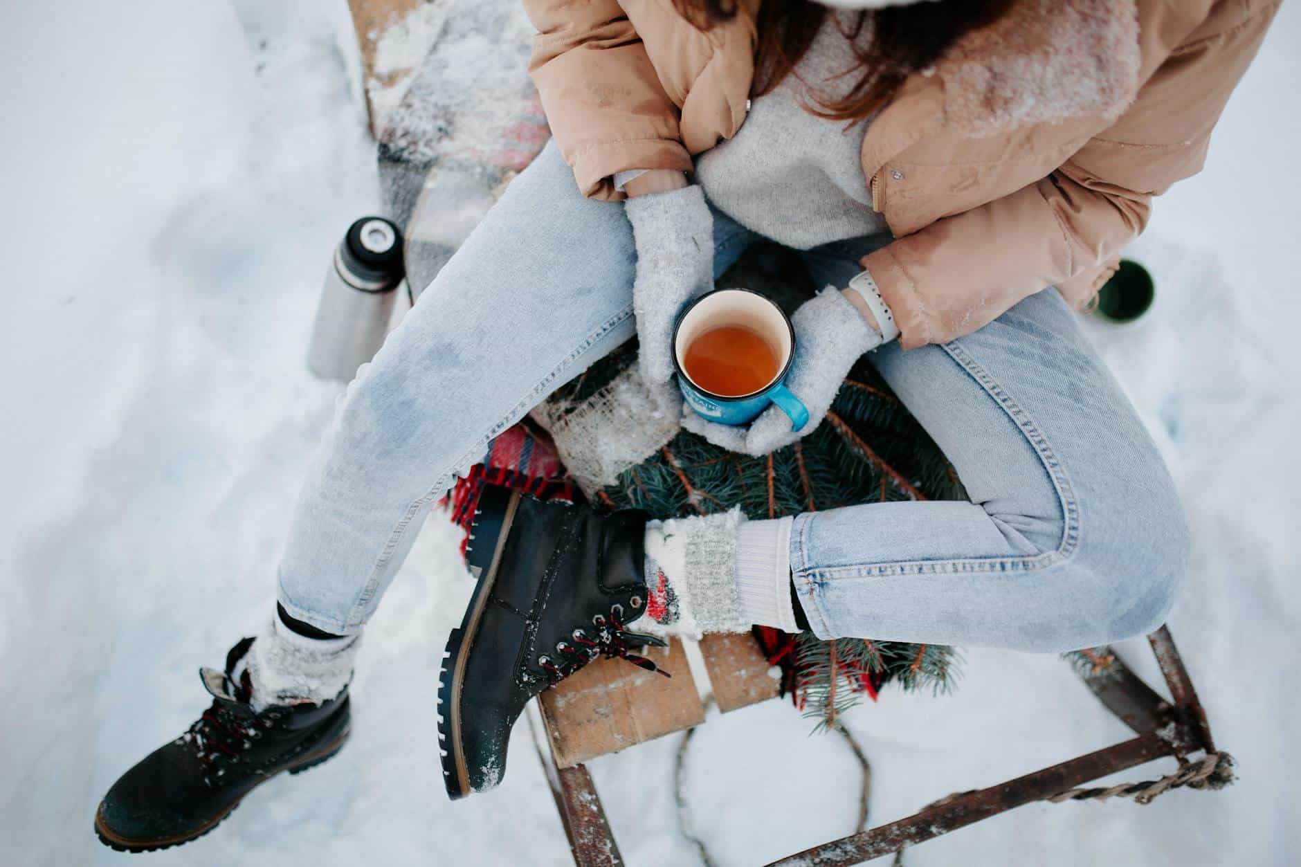 woman sitting on sleight with tea on winter day