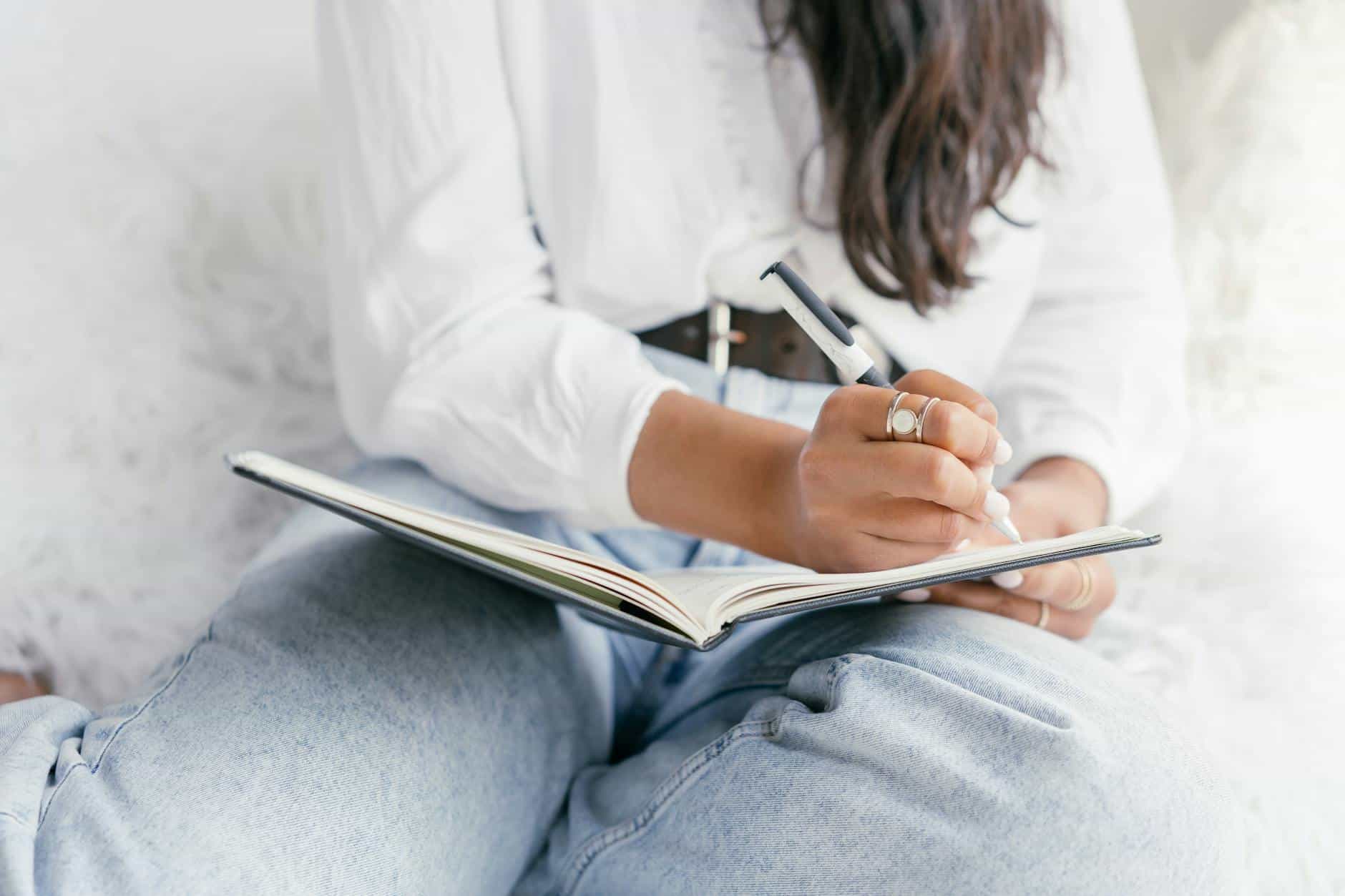 a person in white long sleeve shirt writing on a notebook