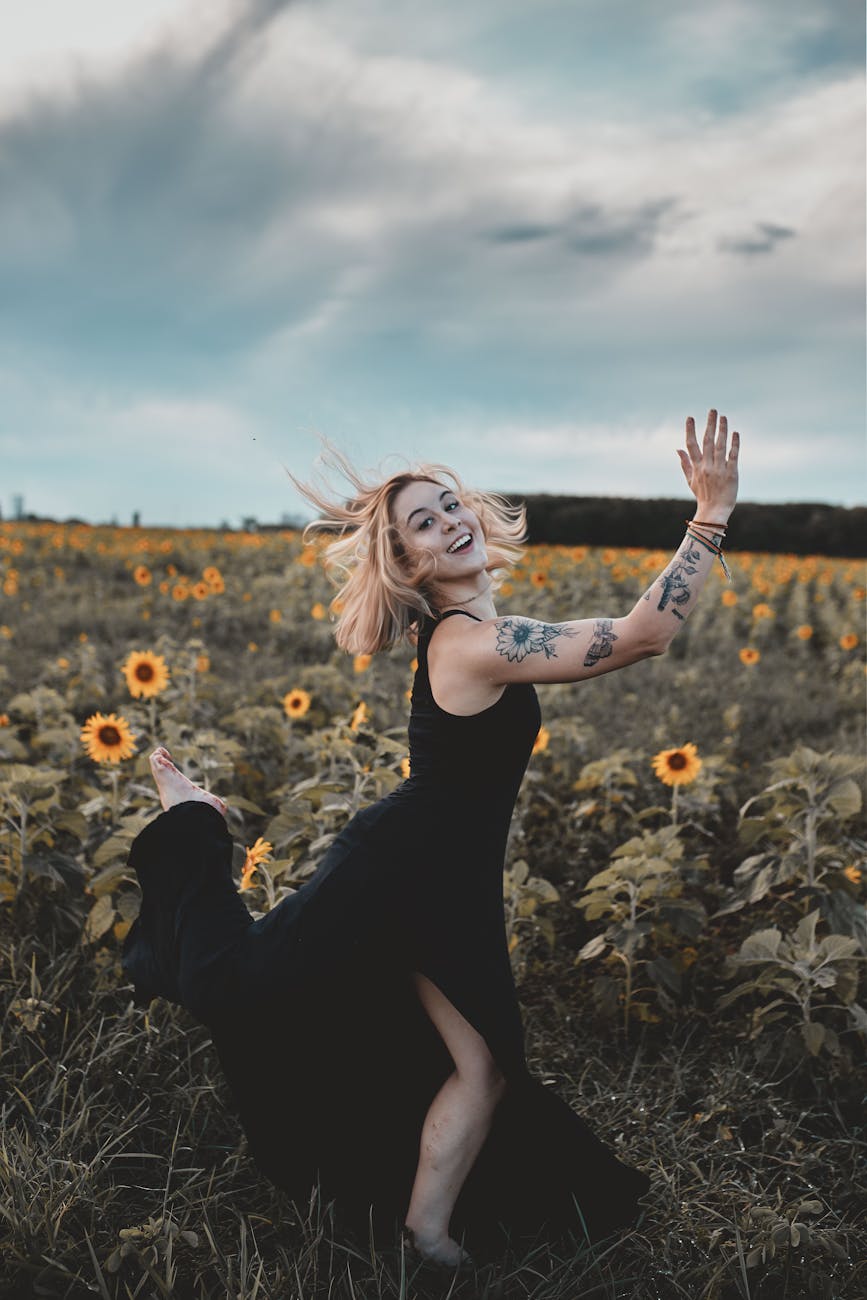 Woman practicing somatic exercises to reduce cortisol outdoors in a sunflower field