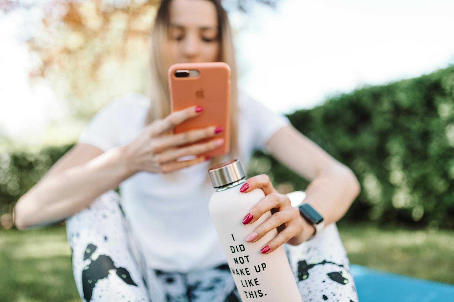 shallow focus photo of a woman taking picture of her water bottle