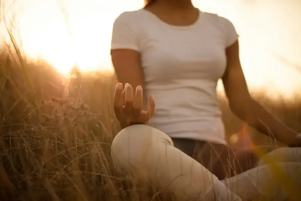 Close up hand meditation at sunset grass