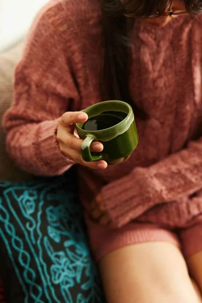 Close up rust sweater holding green mug