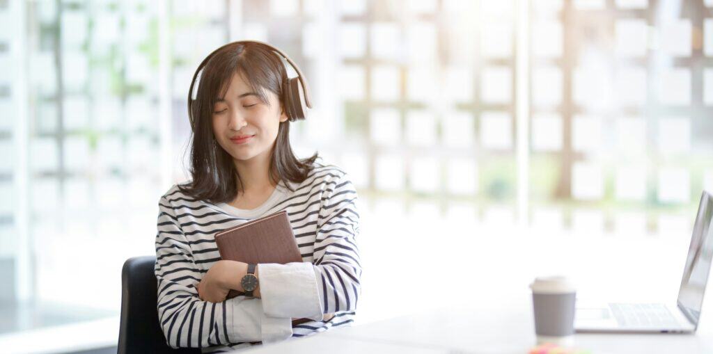 Woman doing a quick body reset at her desk with headphones on.