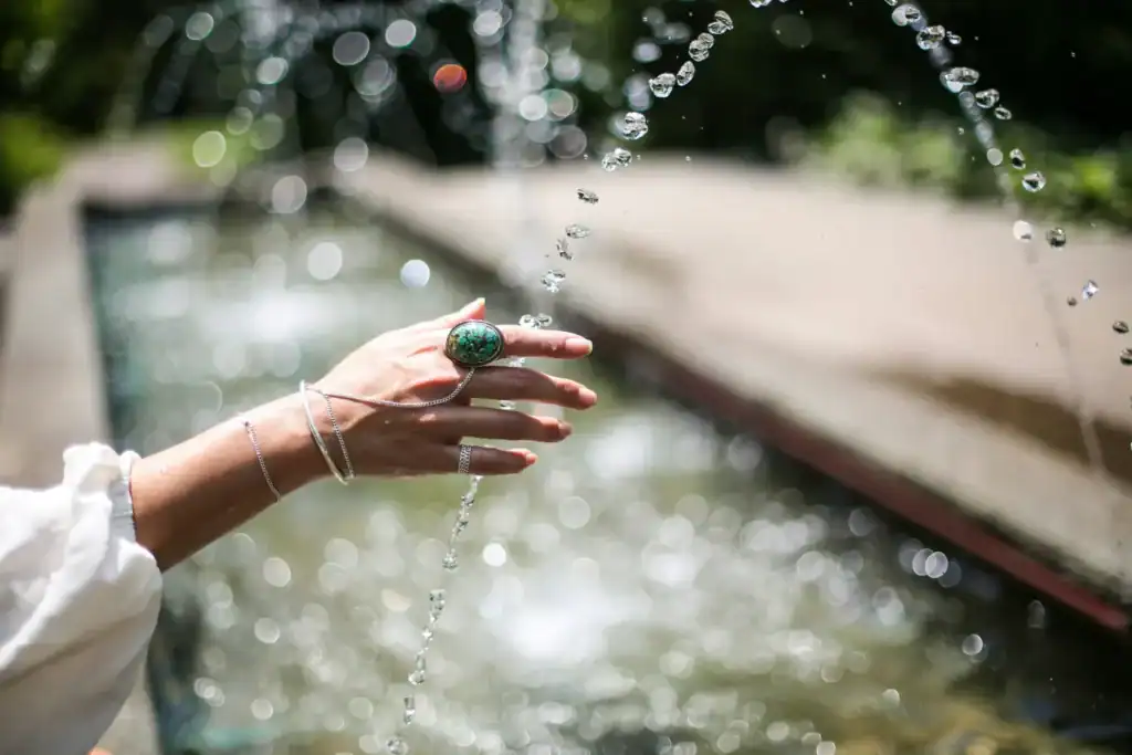 Hand reaching for fountain water spray