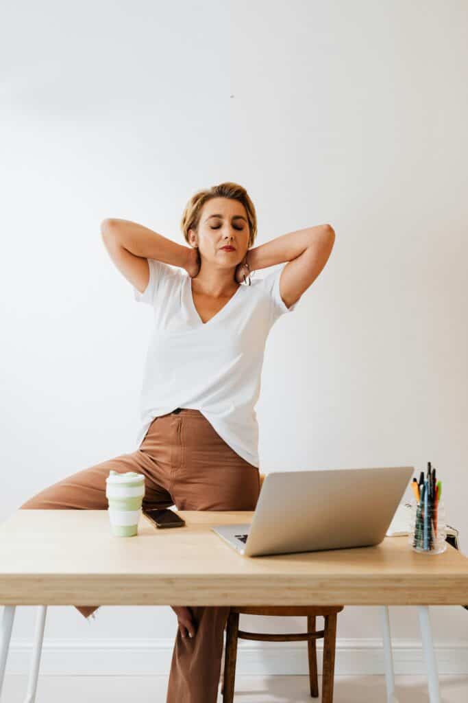 Woman stretching at desk to reduce burnout and refresh during work.