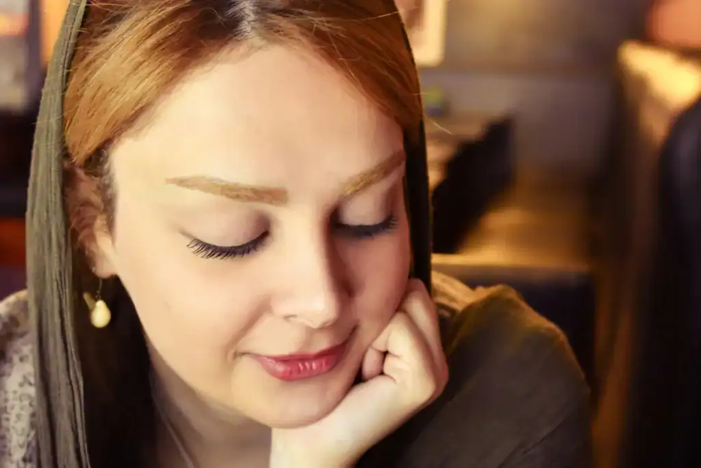 Redhead with olive scarf resting chin eyes closed