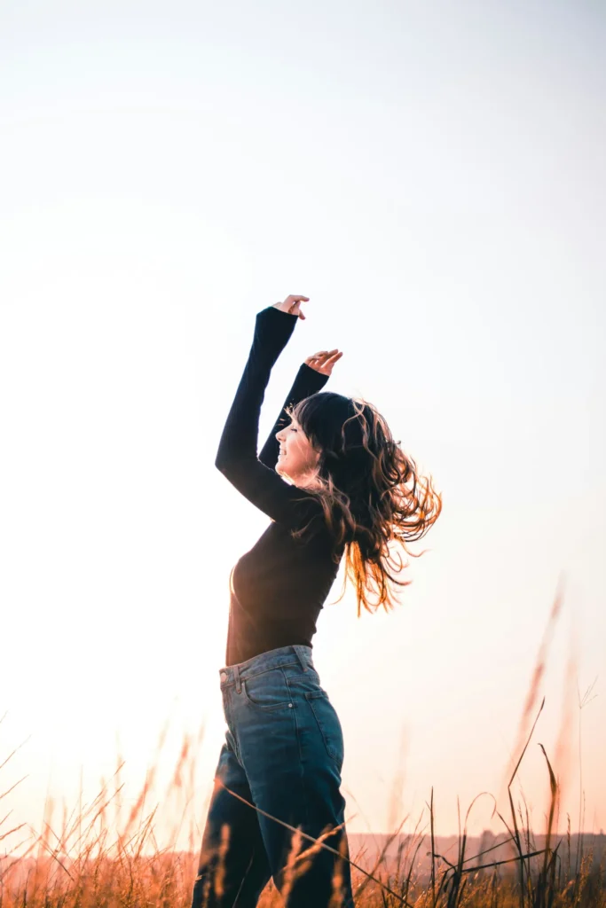 Silhouette woman arms up in sunset field