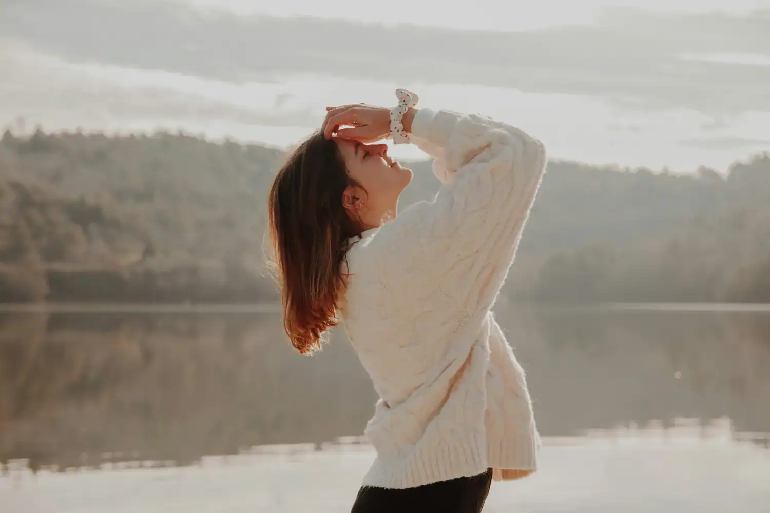 Woman cable knit sweater at misty lake sunrise