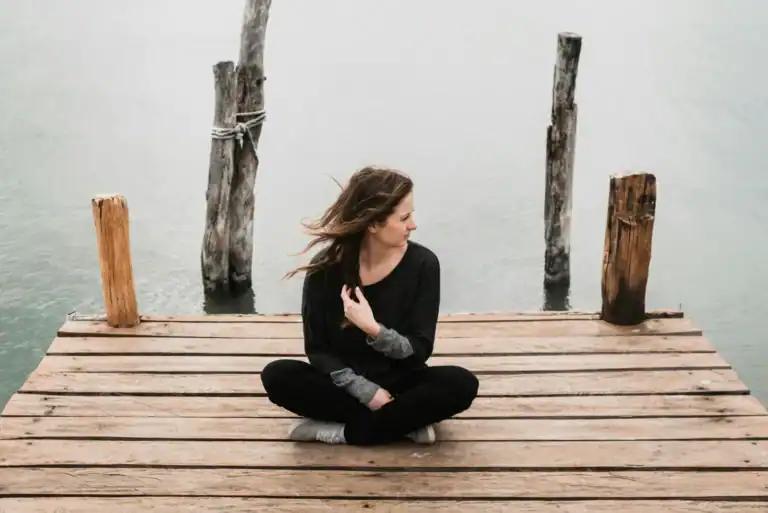 Woman cross legged on dock by lake