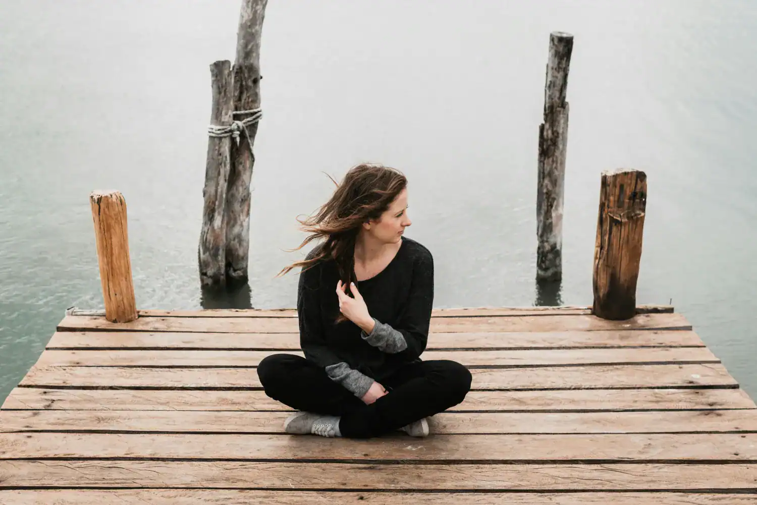 Woman cross legged on dock by lake