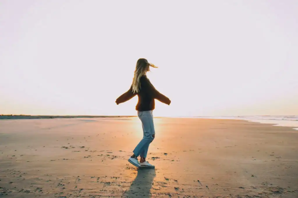 Woman dancing on beach at sunset pastel