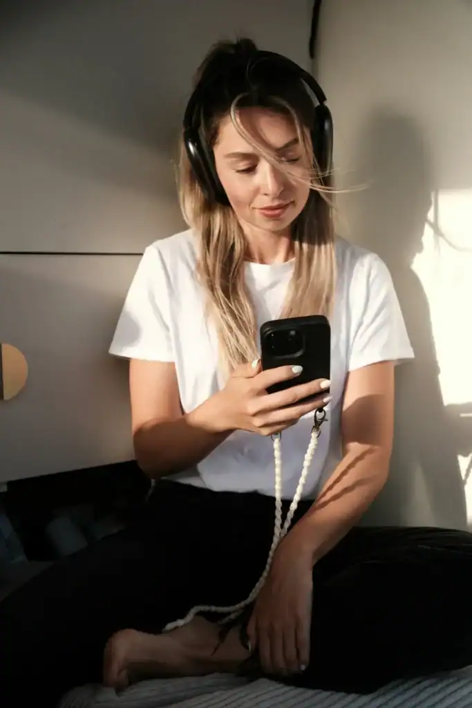 Woman headphones on sunlit bed