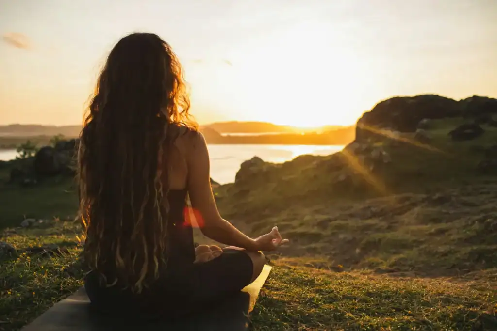Woman meditating lotus pose at sunset