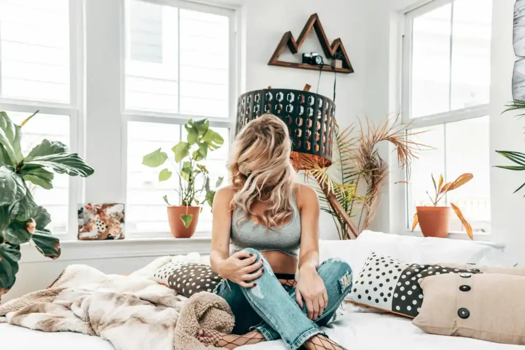 Woman on bed with houseplants grey crop
