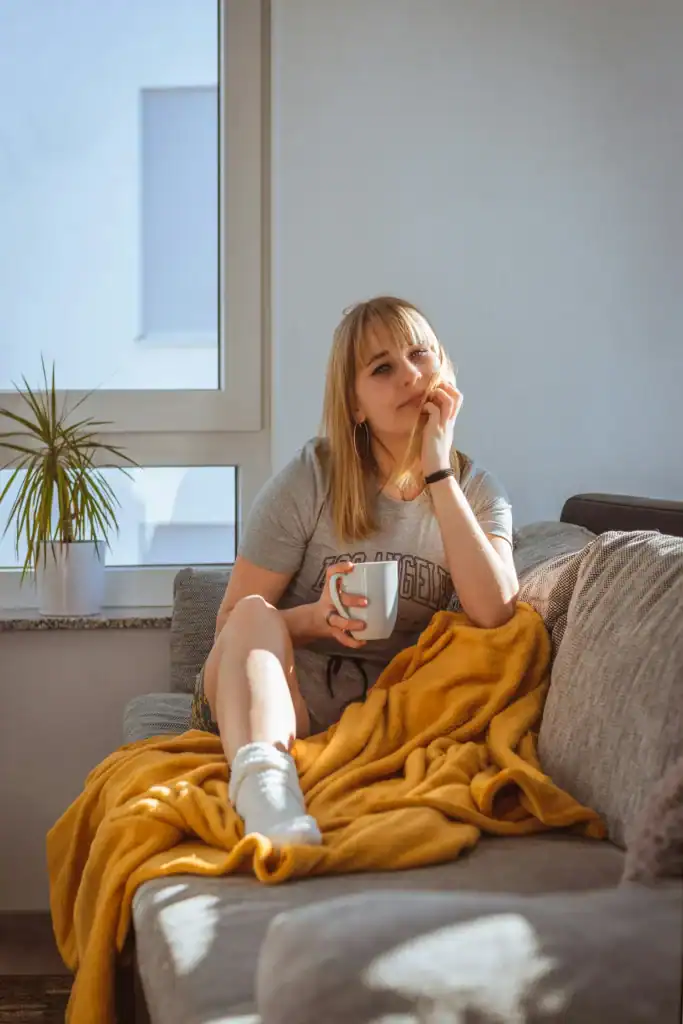 Woman on couch with mustard blanket and mug