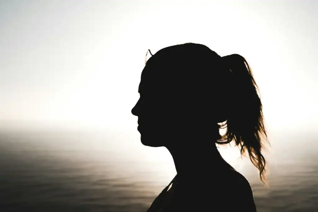 Woman silhouette ponytail at sunset water