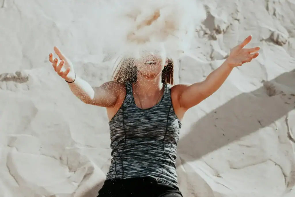Woman tossing sand in air on beach