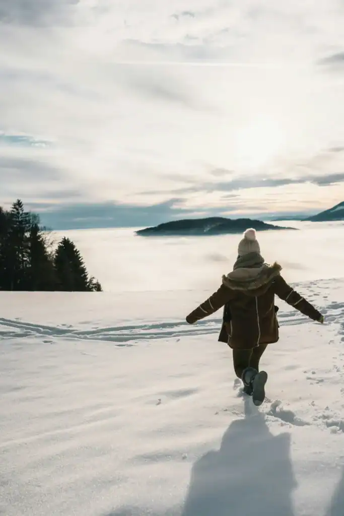 Woman walking in snow toward mountains