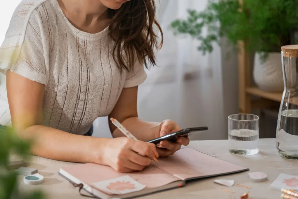 Woman writing in pink journal at table