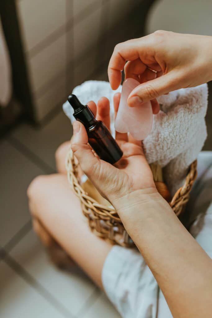 Person using Gua Sha tool with essential oil for relaxation and skin health.
